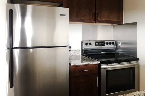A stainless steel refrigerator stands next to a stove in a kitchen.