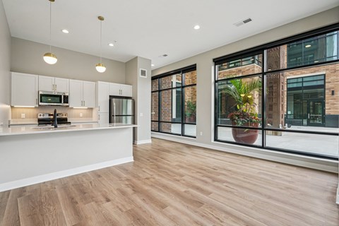 A modern kitchen with wooden floors and a large window.