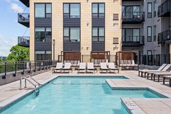 Outdoor pooldeck and spa with lounge chairs and cabanas at Lilia Apartments in Lilydale, MN 55118