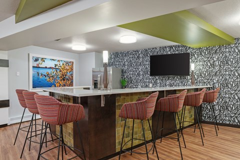 a kitchen with a bar with chairs and a television