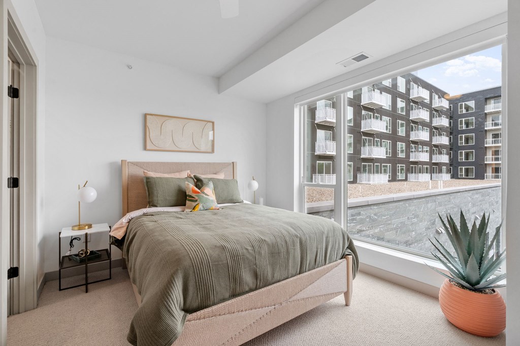 A bedroom with a large bed and a view of a building outside the window. at The Mera, Minnesota