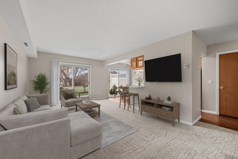 A living room with a grey couch and a flat screen TV mounted on the wall.
