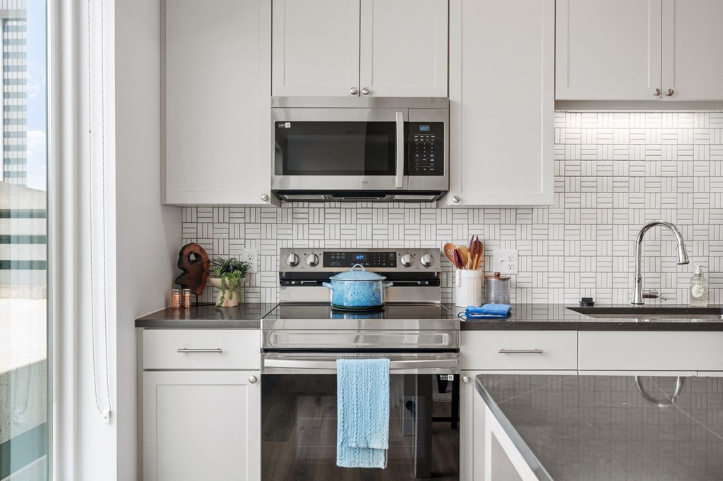 A modern kitchen with white cabinets and a blue towel hanging on the oven. at The Mera, St Louis Park, MN, 55426