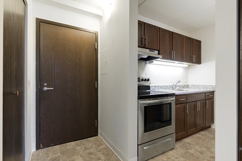 A kitchen with a stove top oven and brown cabinets.