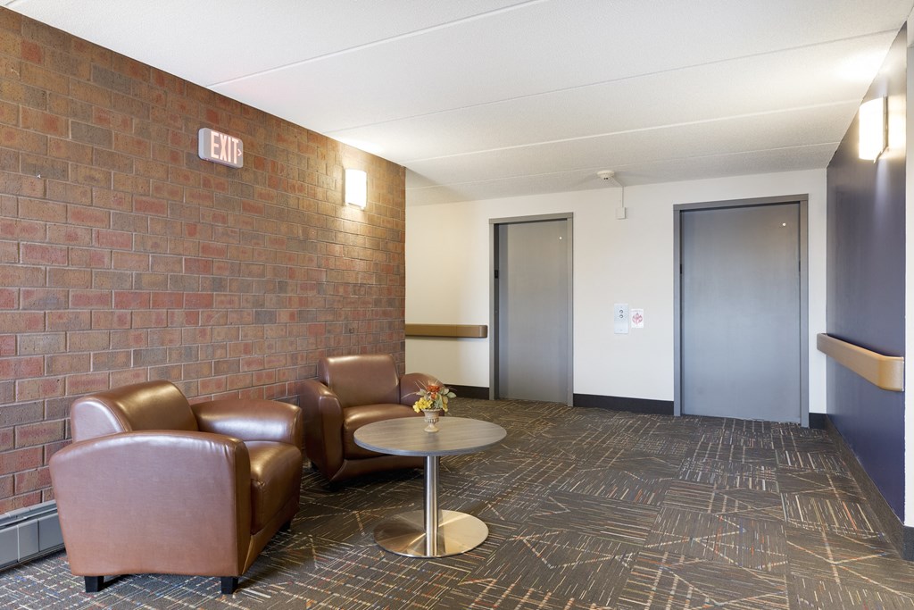 A room with a brick wall and a round table with chairs.