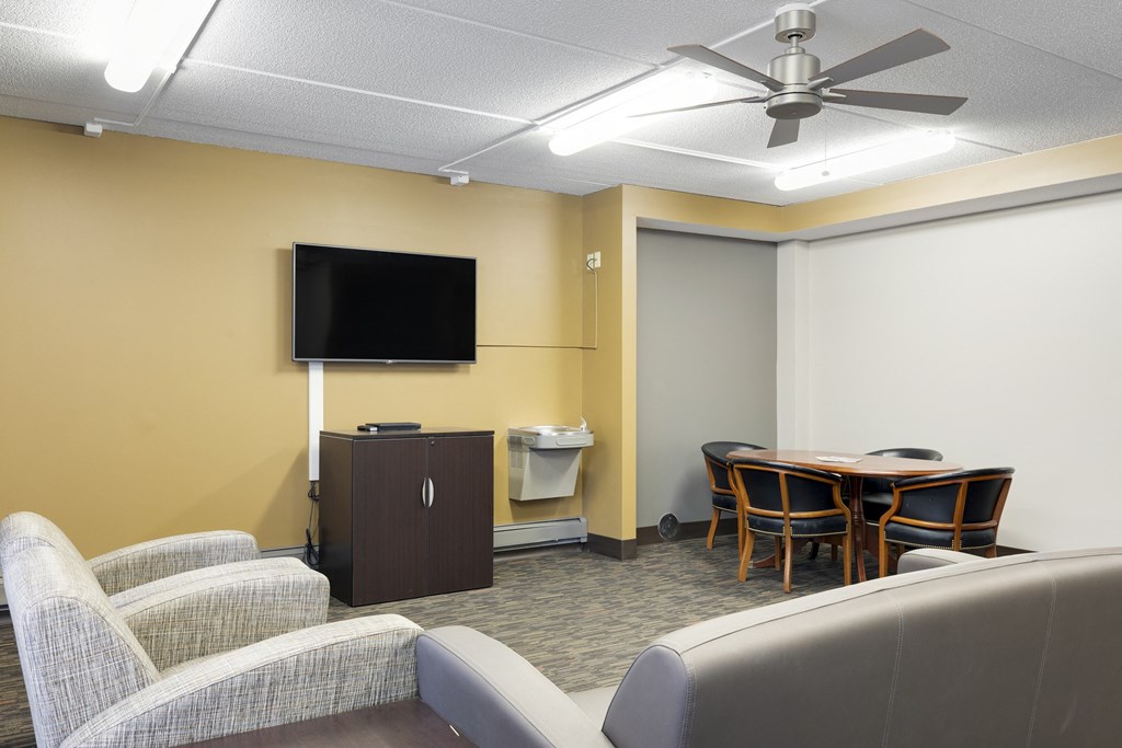 A conference room with a television, chairs, and a table.