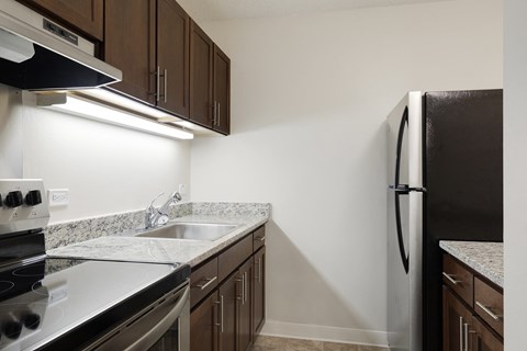 A kitchen with a black refrigerator and a stove top oven.