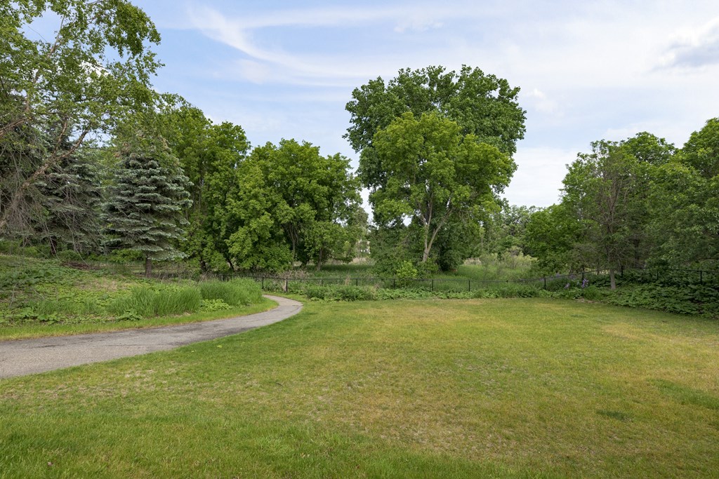 a grassy area with a gravel path and trees in the background  at Shadow Hills, Plymouth, MN, 55442