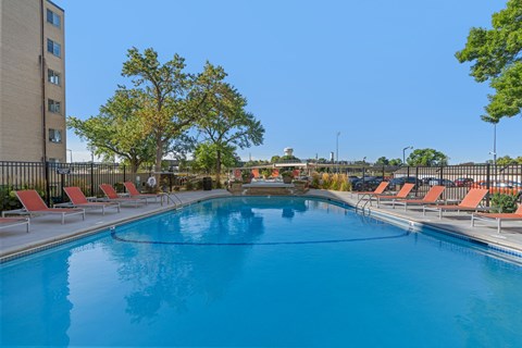 A large outdoor swimming pool surrounded by red lounge chairs.