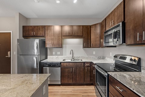 A kitchen with a granite counter top and stainless steel appliances.