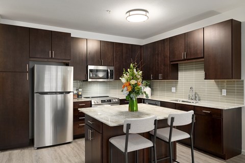Modern kitchen with dark cabinetry and island seating at The Flats at West End Apartments, St. Louis Park