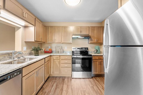 A kitchen with wooden cabinets and a stainless steel refrigerator.