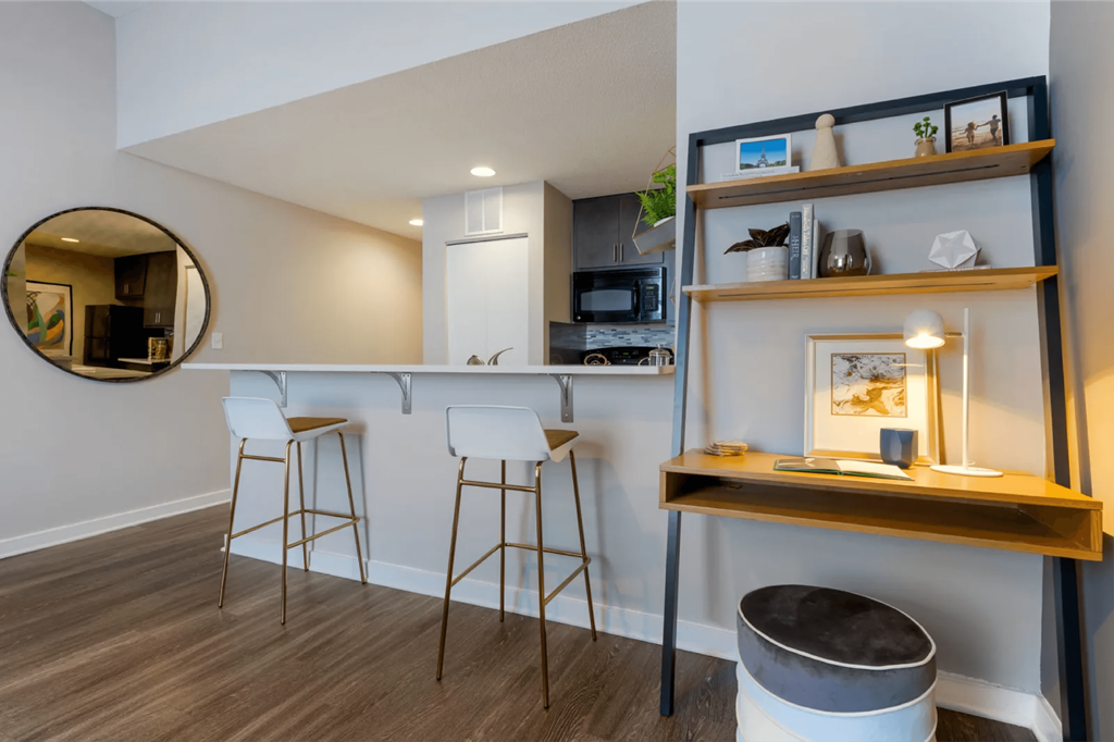a bar area with three stools in front of a kitchen with a counter top  at The Cosmopolitan, St Paul, MN, 55101