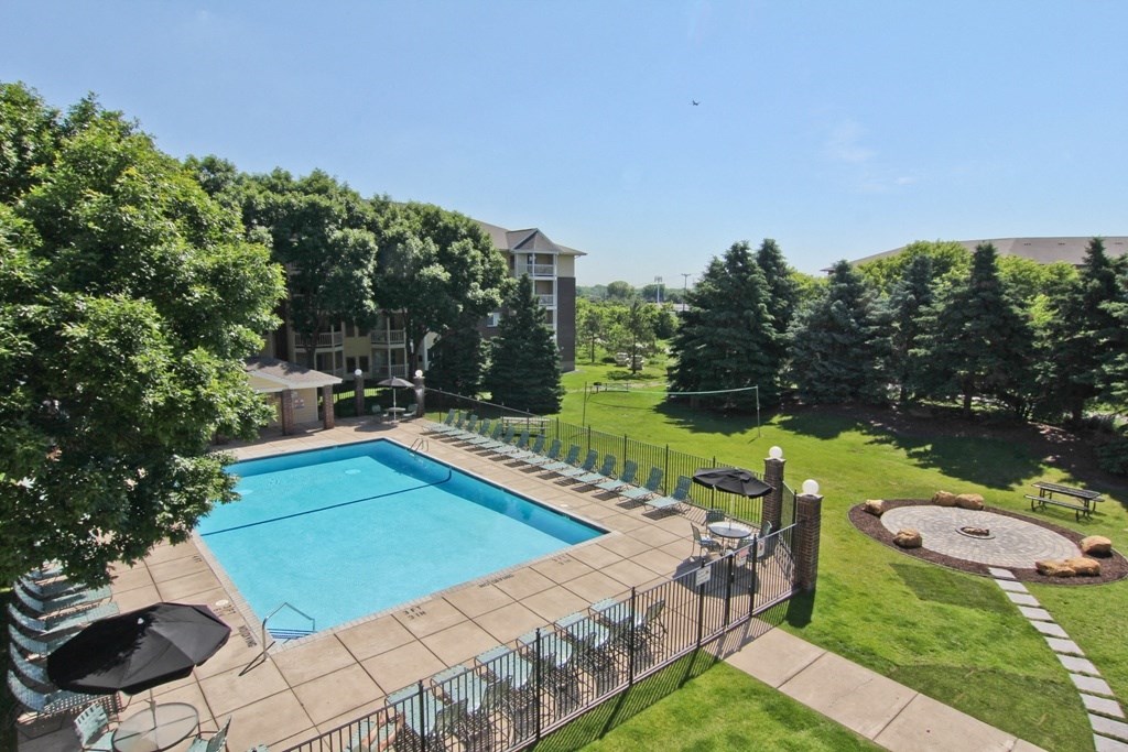 a swimming pool with a fence around it and a lawn with trees at Cityscape, St Louis Park, Minnesota
