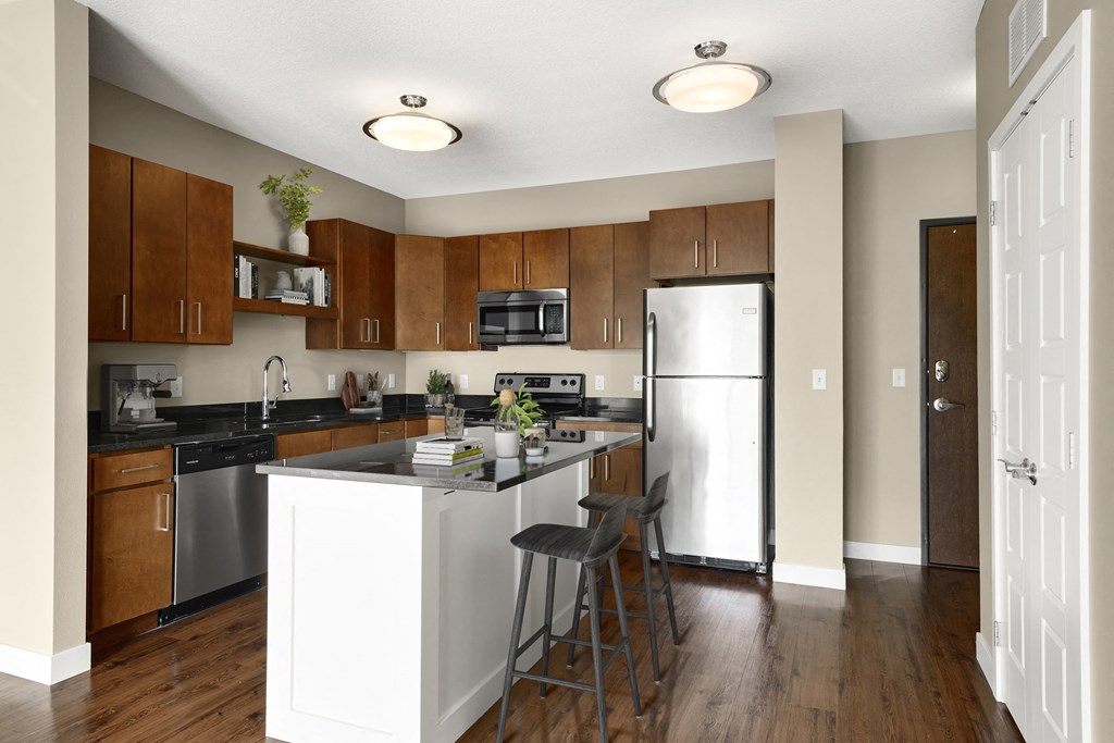a kitchen with a large island with two stools in front of it at Be @ Axon Green, Minneapolis, MN
