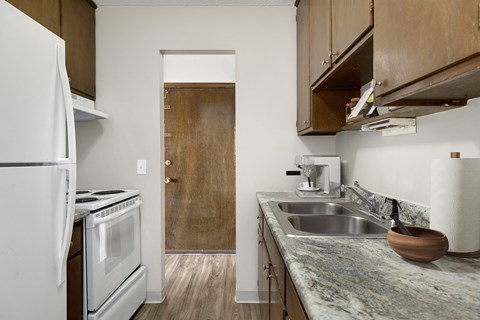 a kitchen with a sink and a refrigerator and a door to a hallway