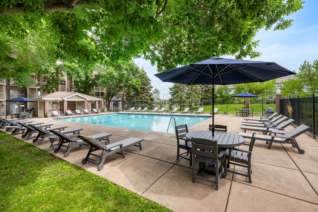 a swimming pool with patio furniture and umbrellas at Cityscape, St Louis Park, MN, 55416