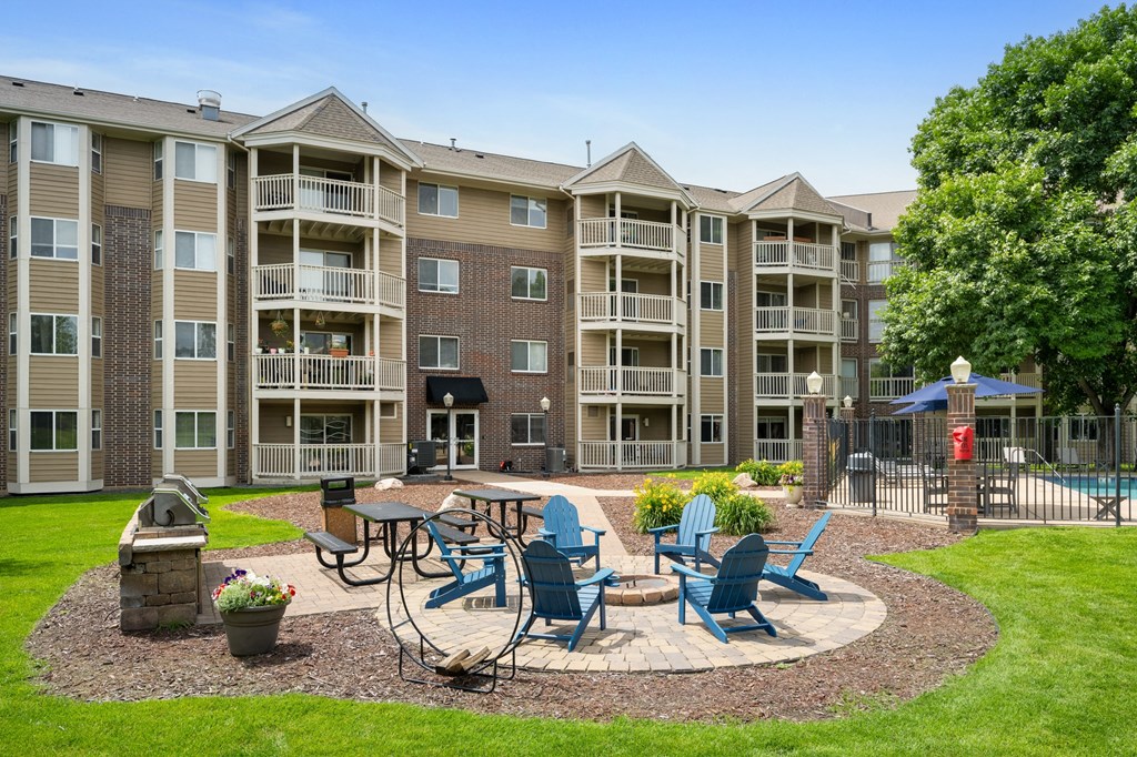 an outdoor patio with tables and chairs in front of an apartment building at Cityscape, St Louis Park, 55416