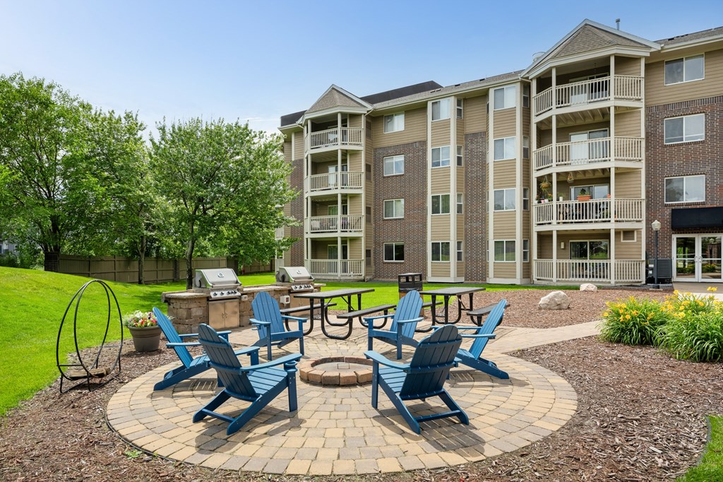 an outdoor patio with blue chairs and a fire pit at Cityscape, St Louis Park, 55416