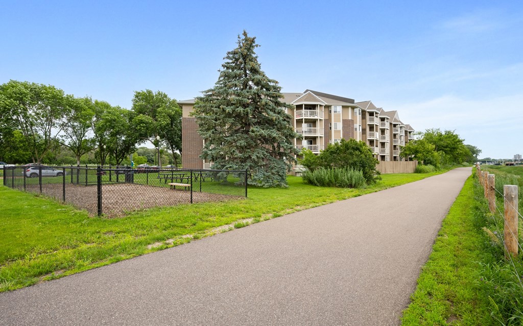 a walkway with a building in the background and a tree in the grass at Cityscape, St Louis Park, 55416