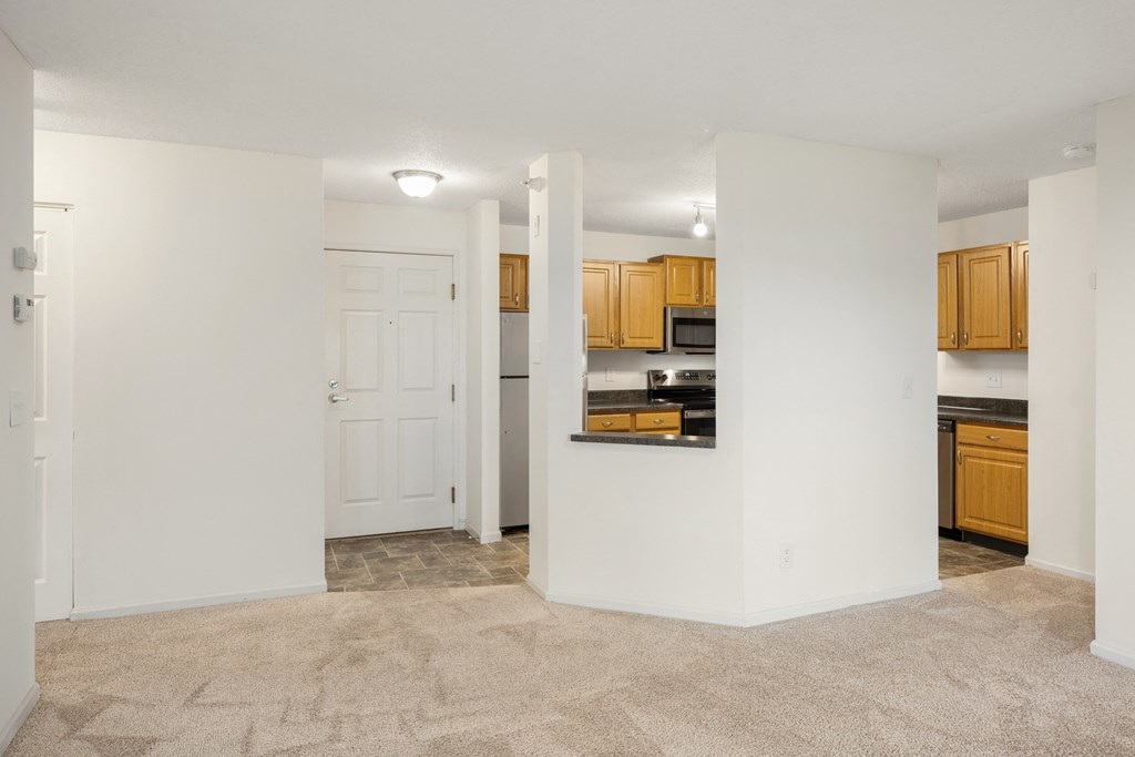 the living room and kitchen of an empty apartment with white walls and wood cabinets at Cityscape, St Louis Park, MN, 55416