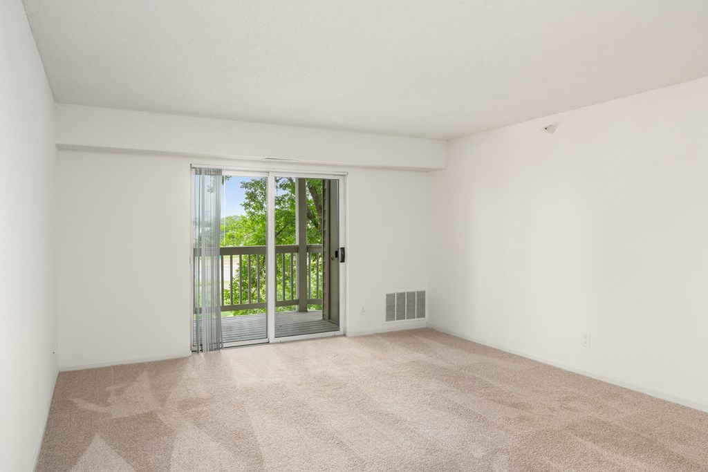 an empty living room with a sliding glass door to a balcony at Cityscape, St Louis Park, MN, 55416