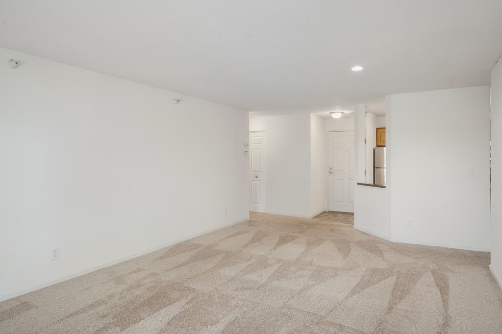 the living room and kitchen of an apartment with white walls and flooring at Cityscape, St Louis Park, 55416