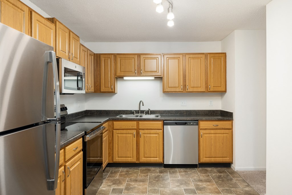 an empty kitchen with wooden cabinets and stainless steel appliances at Cityscape, St Louis Park, MN, 55416