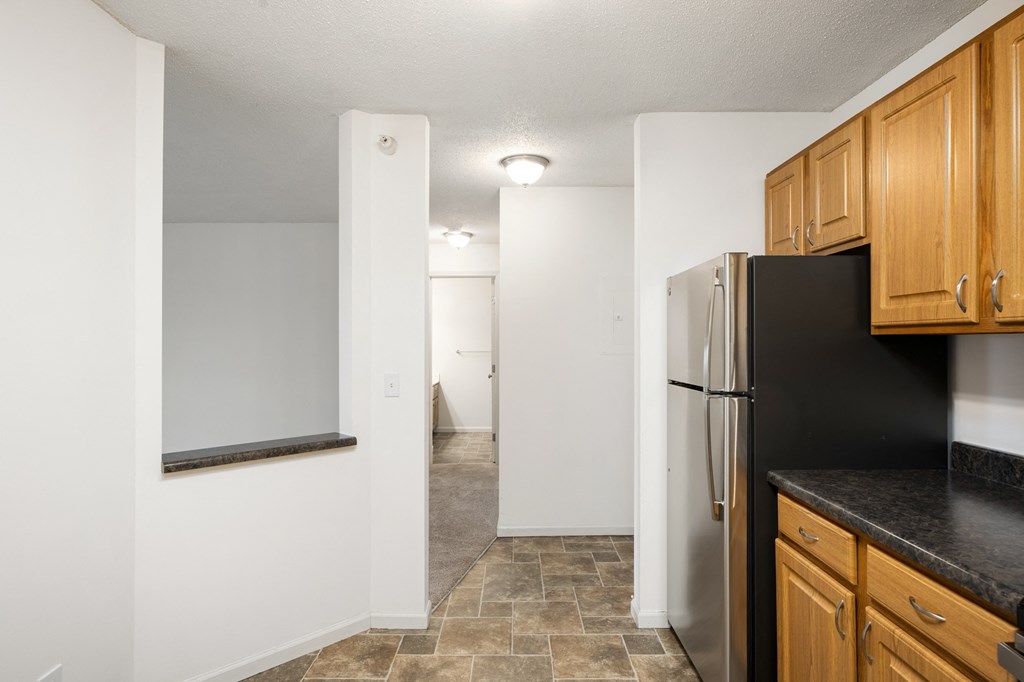 an empty kitchen with a refrigerator and wooden cabinets at Cityscape, St Louis Park, Minnesota