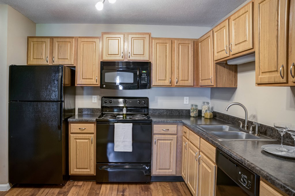 a kitchen with black appliances and wooden cabinets at Cityscape, St Louis Park, 55416