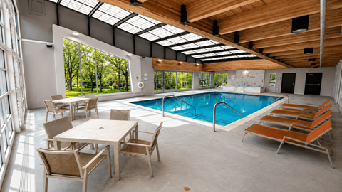 A large indoor swimming pool with lounge chairs and a dining table.