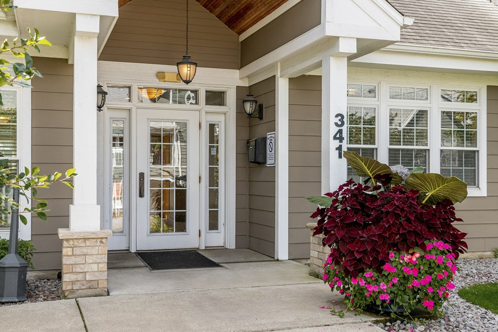 the front door of a home with flowers on the porch