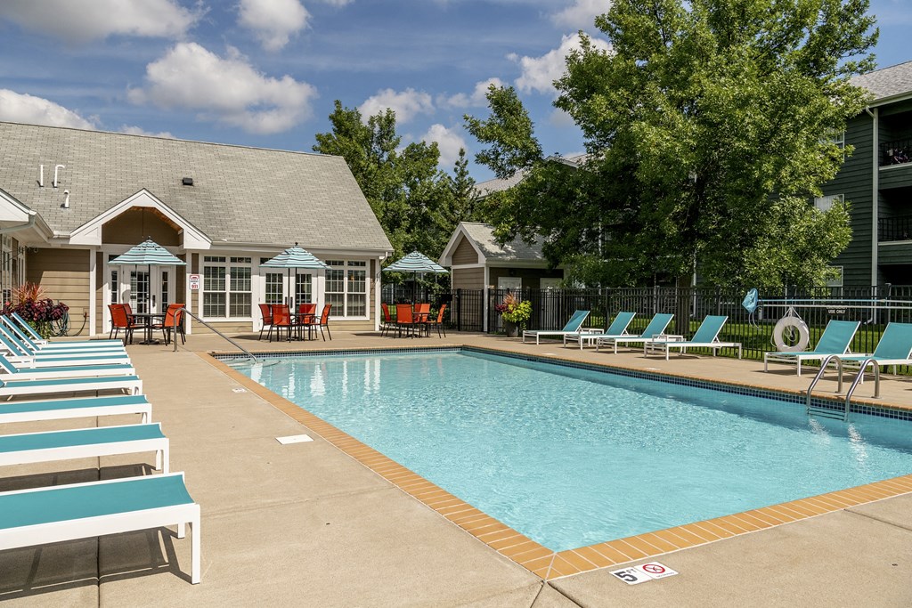 a swimming pool with chairs around it in front of a building