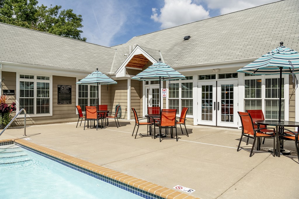 a patio with chairs and umbrellas next to a pool