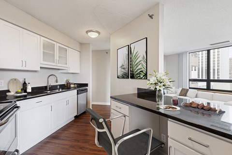 a kitchen and living room with white cabinets and black counter tops