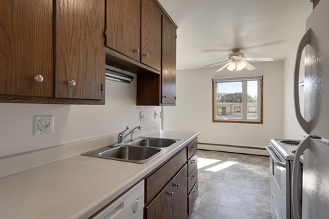 A kitchen with wooden cabinets and a stainless steel refrigerator.