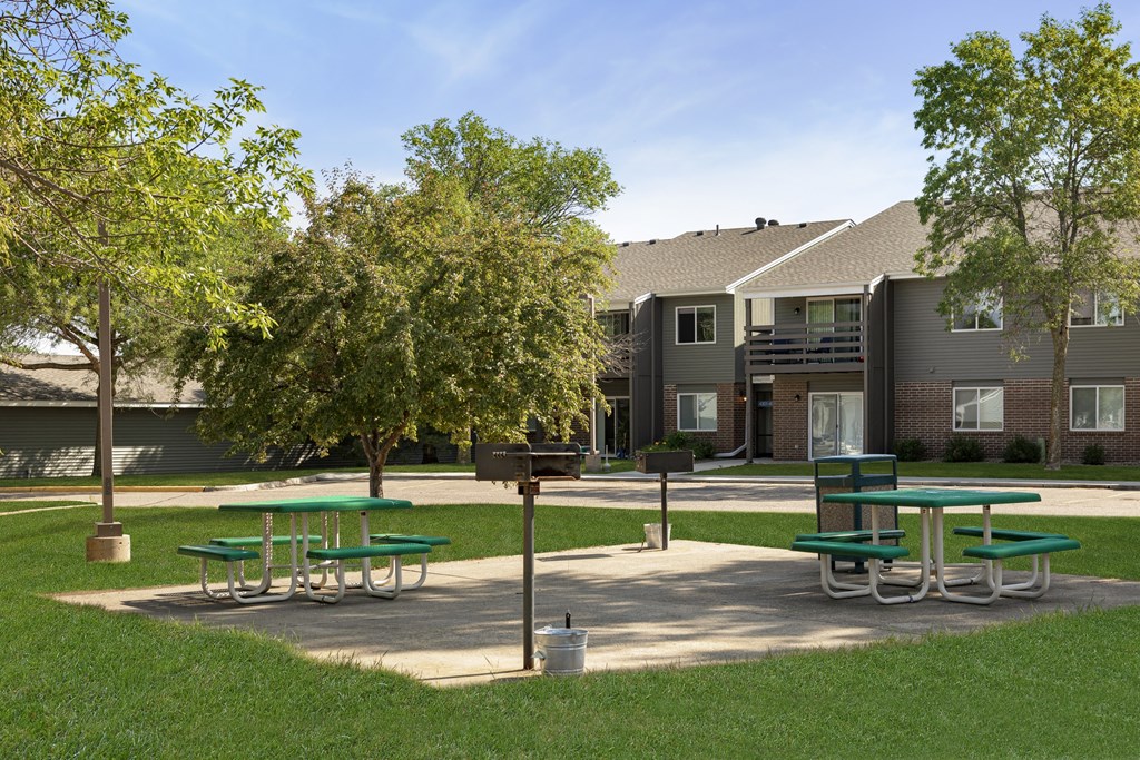 a park with picnic tables in front of an apartment building