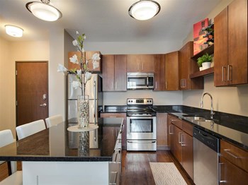 Kitchen Be @ Axon Green Apartment Kitchen with Wood Cabinets, Black Granite Island, and Stainless-Steel Appliances - Photo Gallery 3