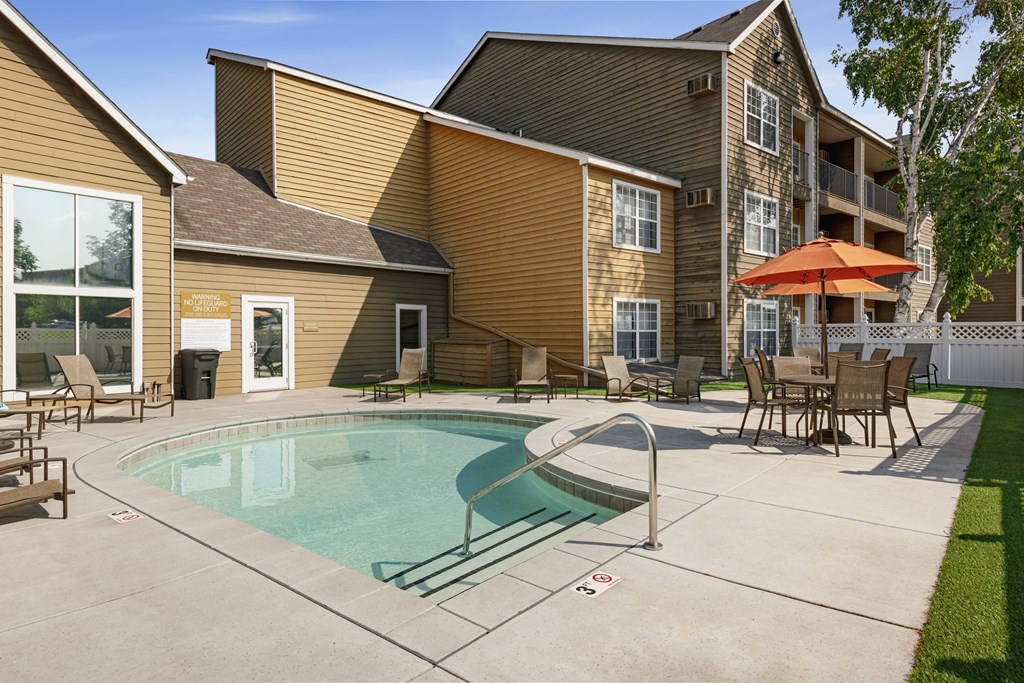 our apartments feature a pool and patio area with tables and chairs