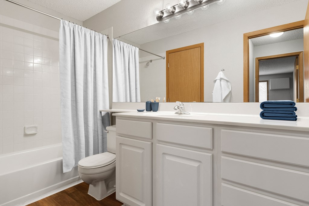 a bathroom with a white shower curtain and a white toilet next to a white bathtub  at Park Pointe, St. Louis Park, MN, 55426