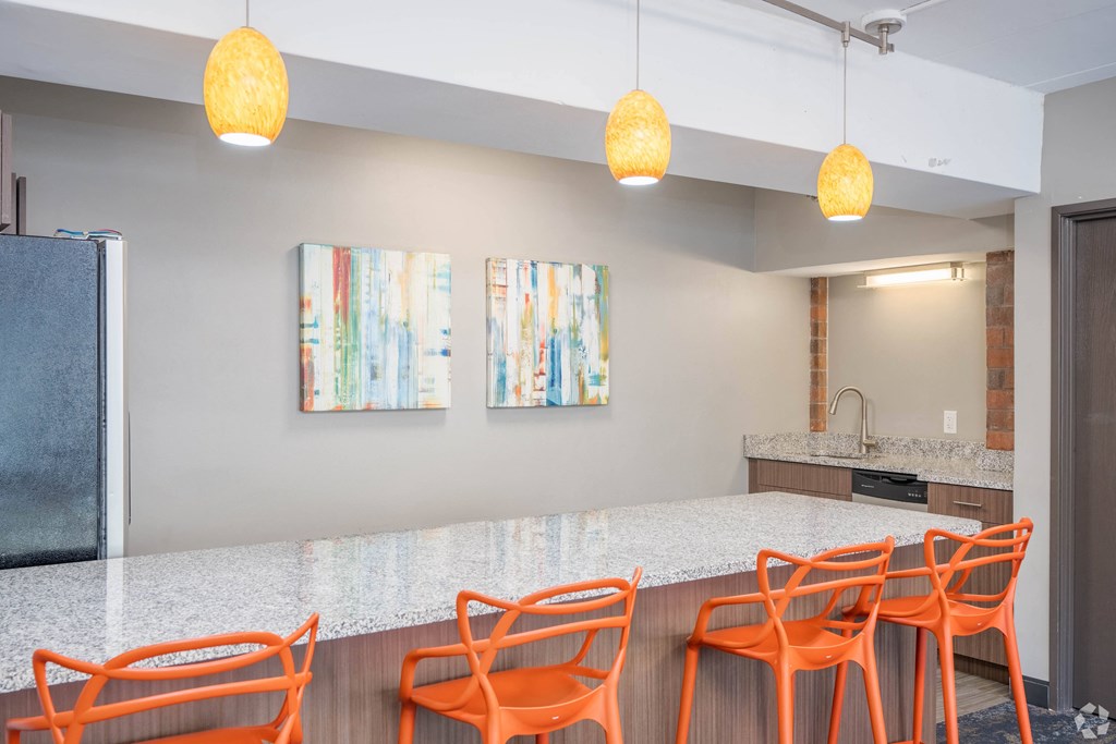 a kitchen with a long counter and orange chairs at Park Pointe, St. Louis Park, Minnesota