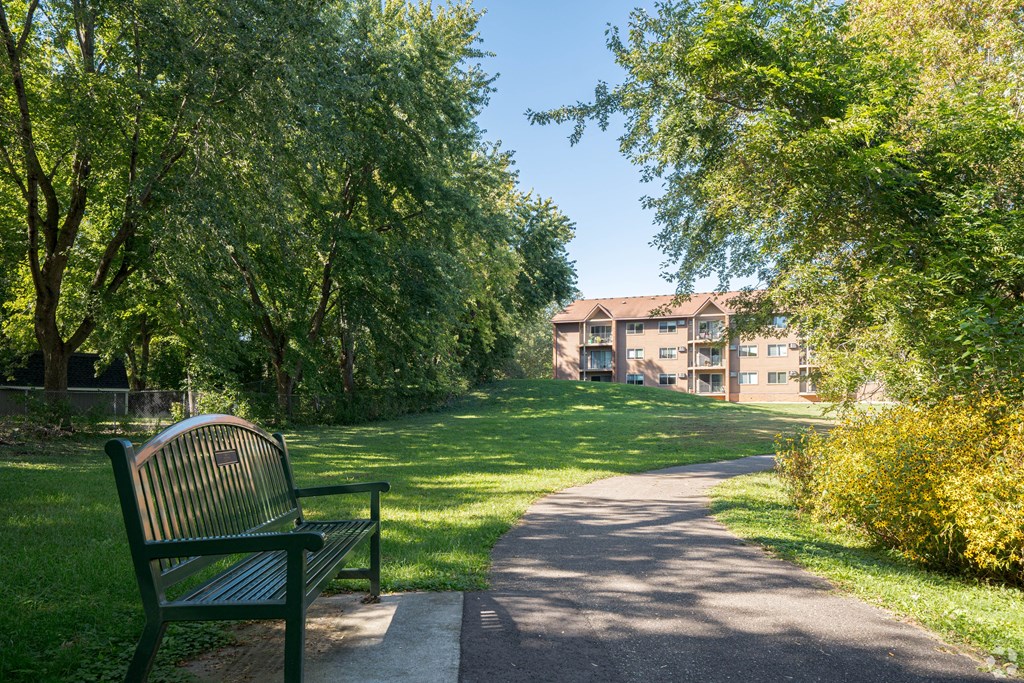 a park bench sitting next to a sidewalk at Park Pointe, St. Louis Park, 55426