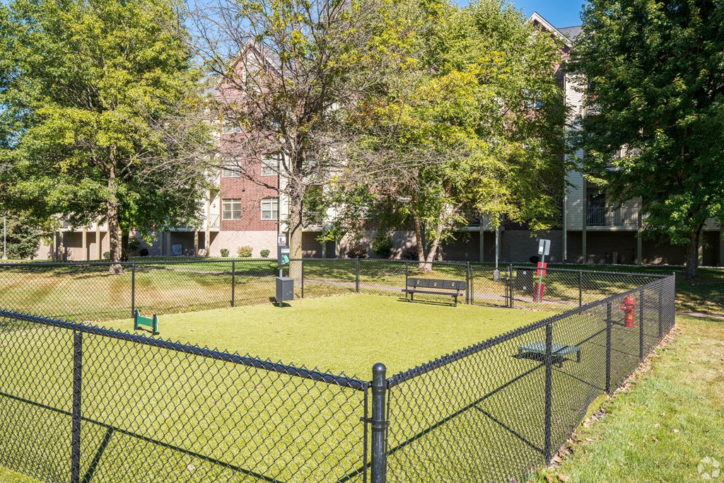 a fenced in area with a tennis court and a bench at Park Pointe, St. Louis Park