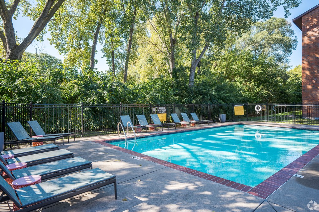 a swimming pool with lounge chairs and trees in the background at Park Pointe, St. Louis Park, MN, 55426