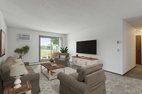 A living room with a grey carpet and a flat screen TV mounted on the wall.