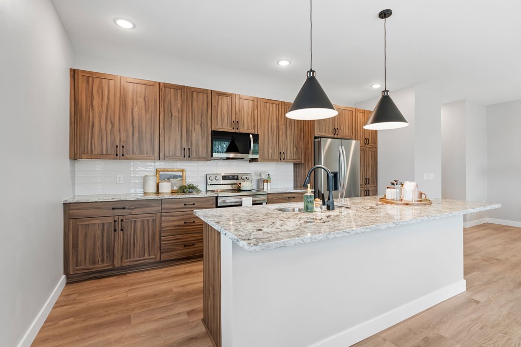 A kitchen with a marble countertop and wooden cabinets. at Townhomes at Preserve, Rogers, Minnesota