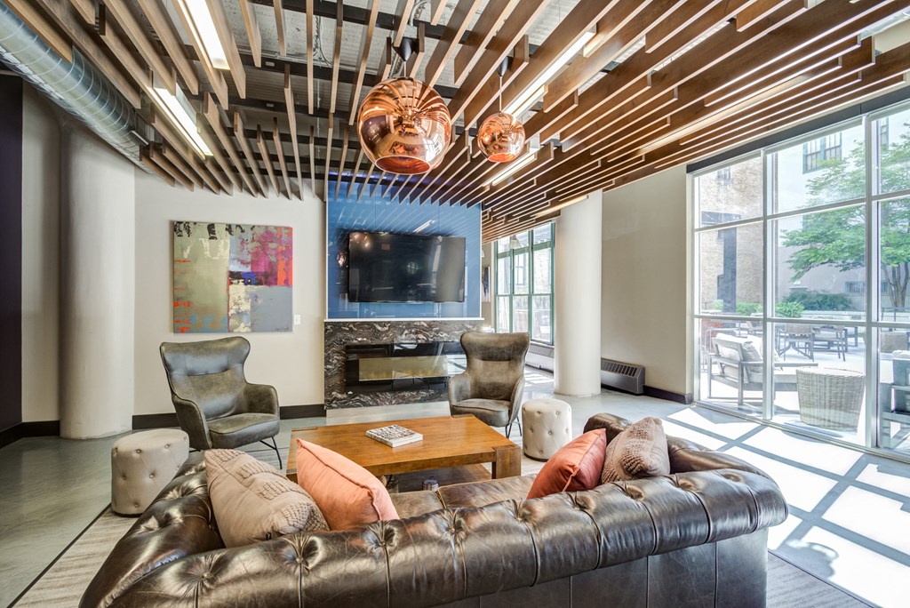 a living room with a brown leather couch and a television  at The Cosmopolitan, Minnesota, 55101