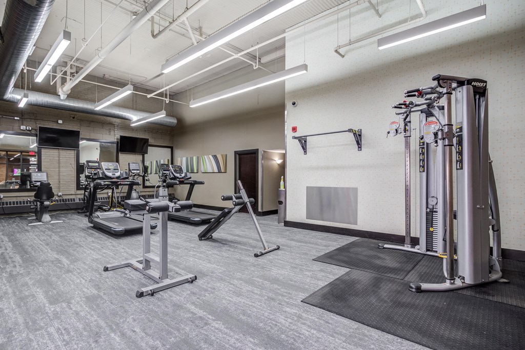 a gym with cardio equipment and weights in a building with white walls  at The Cosmopolitan, St Paul, Minnesota