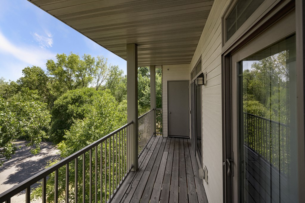 the view from the deck of a home with trees and a door