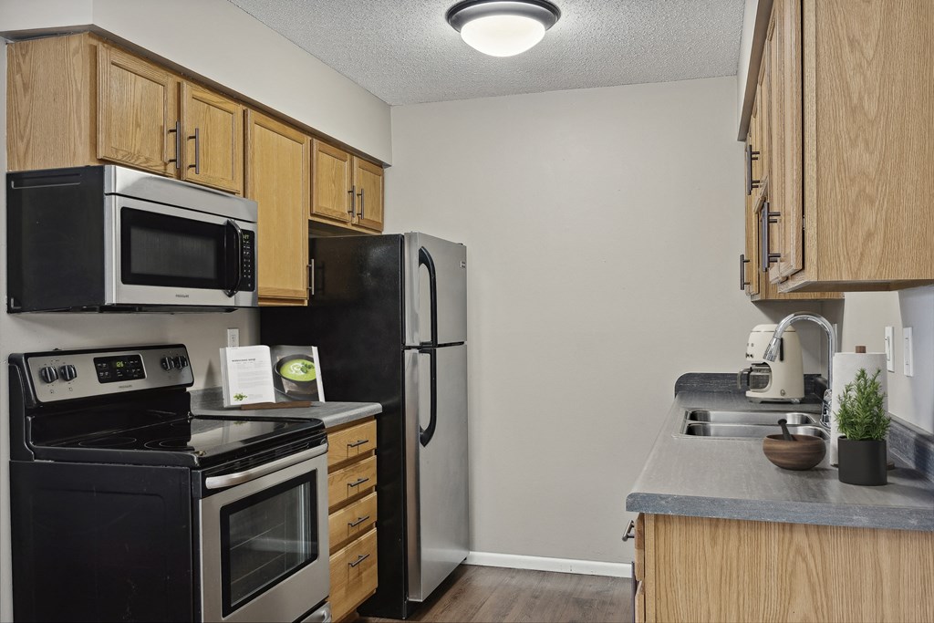 a kitchen with wooden cabinets and stainless steel appliances  at Willow Creek, Plymouth, MN, 55441